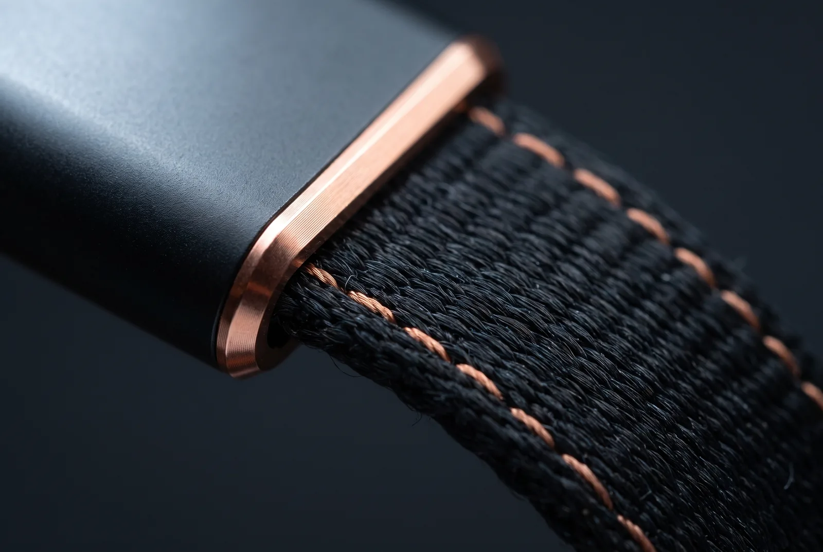 Macro of the woven textile strap meeting its machined copper ferrule.