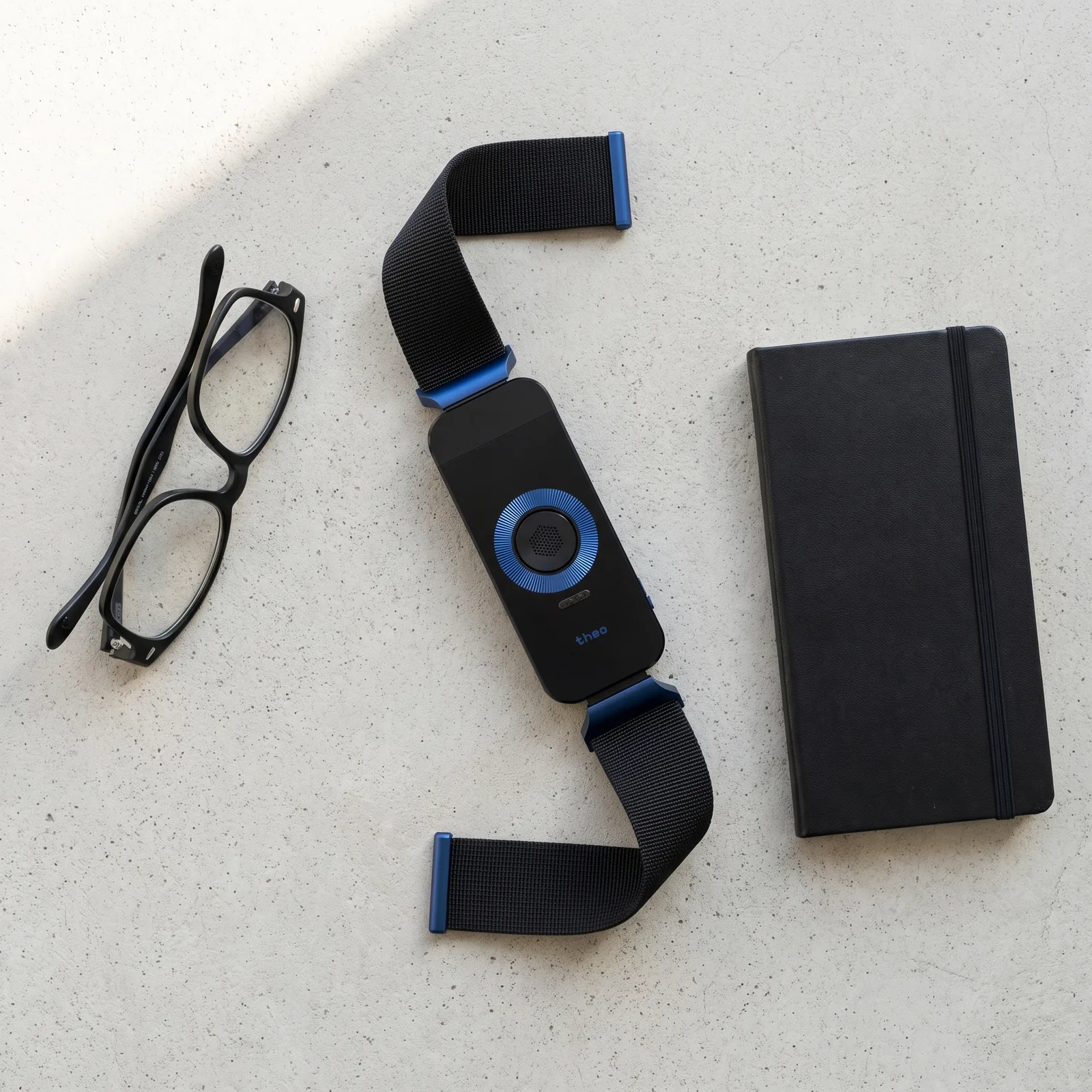 The Midnight band laid on a pale desk beside glasses and a black notebook.
