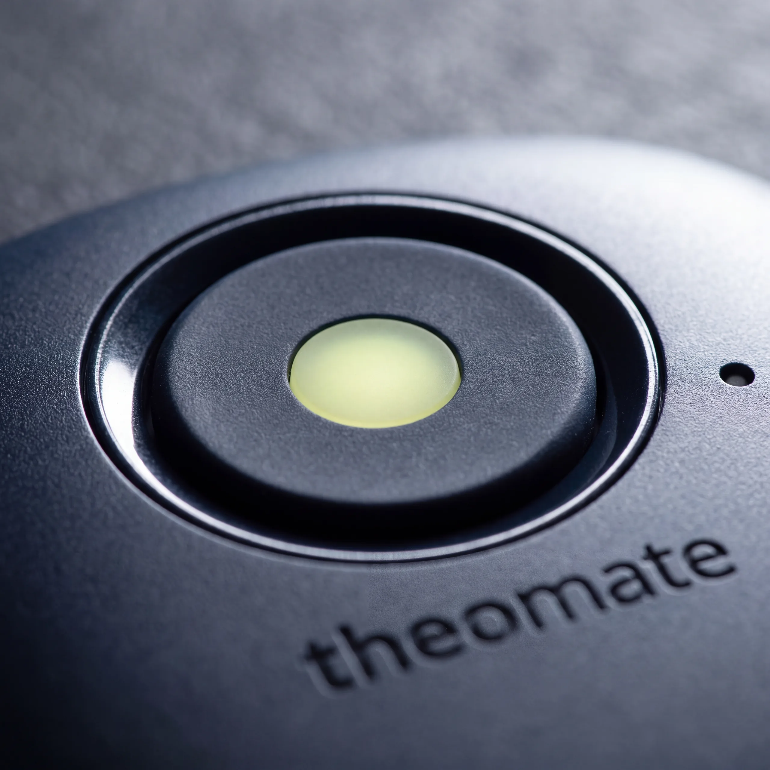 The single round key of the Midnight desk, its ring lit, the theomate wordmark beneath.