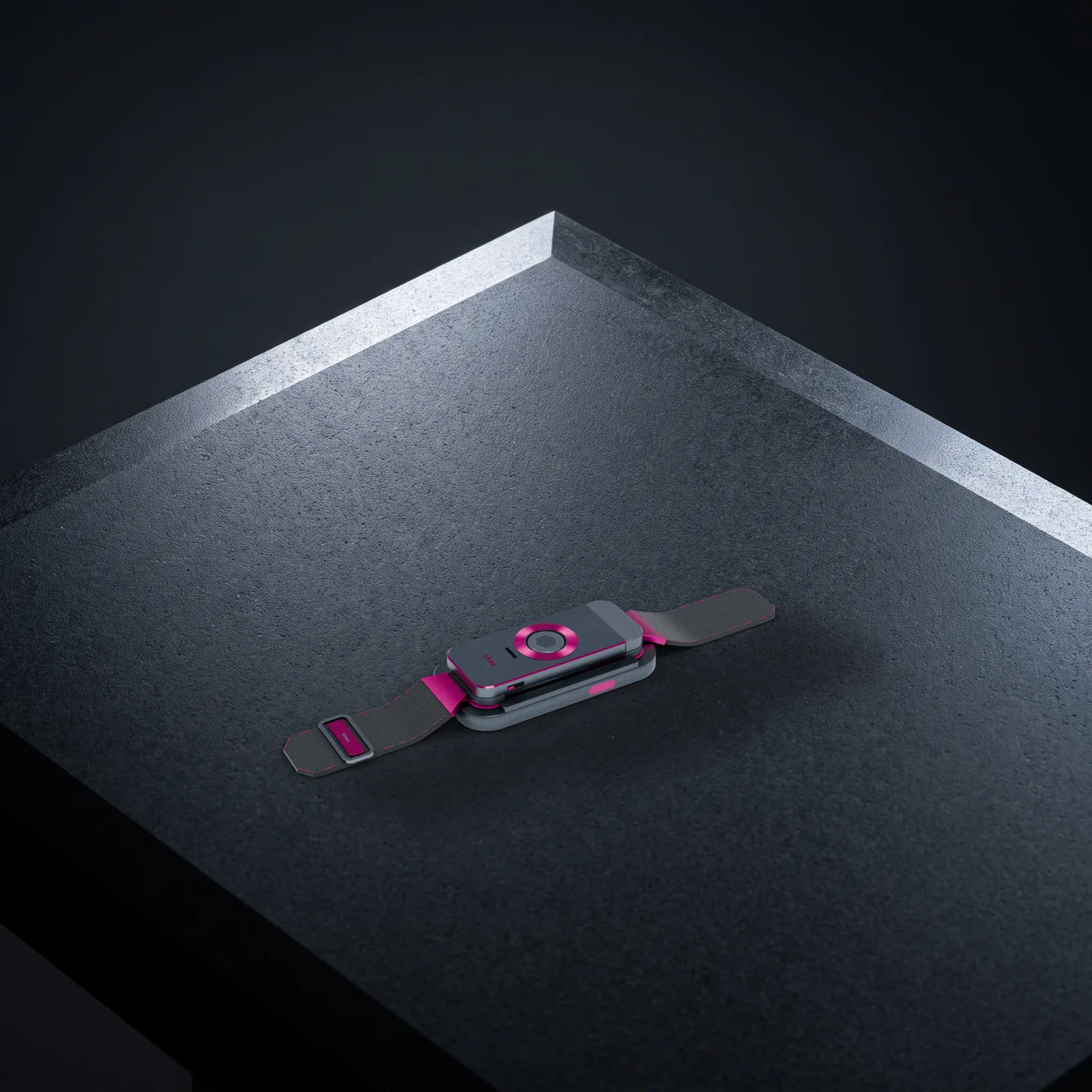 The docked band on a slab of dark honed basalt under a hard studio key light, its edges picked out in white against a graphite background.